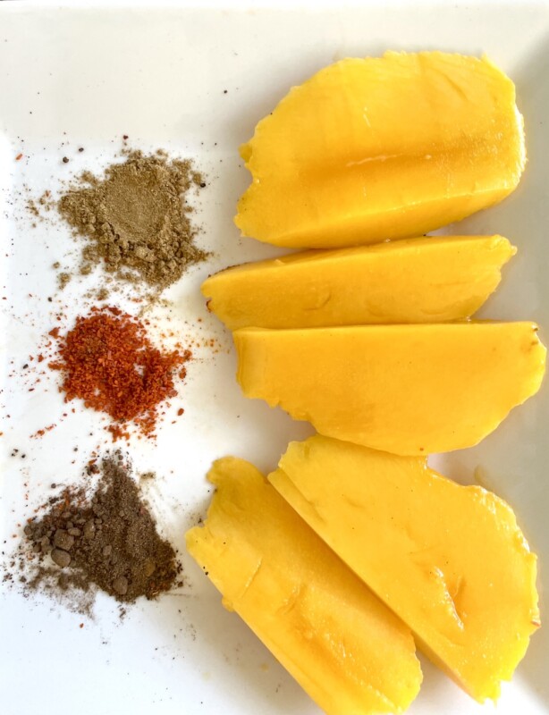 Sliced of mango with various spices for sprinkling. 